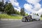 Classic burgundy big rig semi truck tractor transporting cargo in dry van semi trailer driving on the wide highway road with