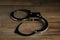Classic chain handcuffs on wooden table, closeup