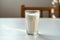 Classic composition Glass of milk, side view, on white table