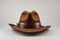 Classic cowboy brown felt hat with strap and copper closure on white background