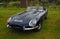 Classic Dark Blue 1965 Jaguar E Type Convertible  isolated parked on grass.