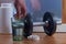 Classic dumbbell with a glass of water and a set of pills. Male hand puts a vitamin pill into a glass