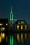 Classic dutch houses along a river with illuminated communication tower in the background