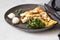 Classic egg omelette or omelet served with mushrooms, mozzarella and microgreens on black ceramic plate. Breakfast. Light grey