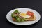 Classic eggs and bacon meat on waffles breakfast with tomatoes and salad served on a white plate on black background.