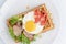 Classic eggs and bacon meat on waffles breakfast with tomatoes and salad served on a white plate on black background.