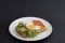 Classic eggs and bacon meat on waffles breakfast with tomatoes and salad served on a white plate on black background.