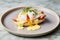 Classic eggs Benedict on gray plate on light background, Closeup