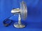 Classic Electric Table Fan. Chrome, retro,  front view, closeup, isolated against blue background.