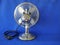 Classic Electric Table Fan. Chrome, retro,  front view, closeup, isolated against blue background.