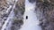Classic gray car driving through the white winter snowy forest on country road. Top view. Winter or alpine road in the