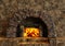 Classic isolated rustic fireplace made of stones lit with orange fire flames