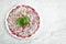 Classic Italian appetizer - veal carpaccio with arugula and parmesan served on a white plate on a marble background. Thinly sliced
