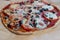 Classic Italian pizza with mozzarella, tomatoes, olives and chopped salami