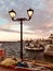 A classic lamp post illuminates a sunset in a village in Paros, Greece