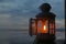 Classic lantern and candle light inside with opened window on night blue sky background at dusk in the beach.