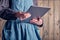 A classic large tablet in female hands in a beautiful cotton dress and a linen emerald apron.