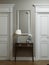 Classic modern hallway corridor interior with beige walls and white doors. Key table and a large mirror with sconces on the wall