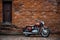 classic motorbike parked in front of a rustic brick wall