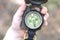 Classic navigation compass in childs hand on natural background