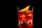 Classic Negroni in a crystal-cut rocks glass isolated on black backdrop