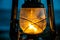 Classic oil lantern burning a bright flame at sunset on a beach