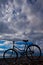 Classic old bicycle by the sea, blue sky with clouds, contrasting silhouette of a bicycle