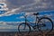 Classic old bicycle by the sea, blue sky with clouds, contrasting silhouette of a bicycle