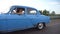 Classic old car traveling on highway on summer day. Young couple driving on country road in vintage automobile. Trip at