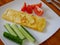 Classic omelet with tomatoes and cucumbers on the white plate.