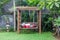 Classic outdoor wooden swing in the green garden with pillows.