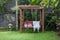 Classic outdoor wooden swing in the green garden with pillows and blanket.