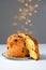 Classic panettone with dried fruits, traditional Italian Christmas cake on gray background with fairy lights. Before the piece, a