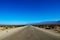 Classic panorama view of an endless straight road running through the barren scenery of the American Southwest with extreme heat