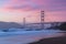 Classic panoramic view of famous Golden Gate Bridge seen from scenic Baker Beach in beautiful golden evening light on a dusk