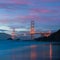 Classic panoramic view of famous Golden Gate Bridge seen from scenic Baker Beach in beautiful golden evening light on a dusk