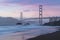 Classic panoramic view of famous Golden Gate Bridge seen from scenic Baker Beach in beautiful golden evening light on sunset.