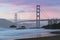 Classic panoramic view of famous Golden Gate Bridge seen from scenic Baker Beach in beautiful golden evening light on sunset.