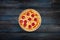 Classic pepperoni pizzai on a wooden stand on a dark wooden background. Top view center orientation