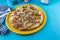 Classic pizza with mussels, meat, green olives, cheese. yellow plate on a blue table. Cafe menu. Fork, knife and place for text.