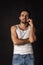 Classic portrait of young handsome bearded sad man in white undershirt and jeans isolated on dark background. Emotions