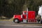 Classic powerful red big rig semi truck running on the road with