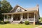 classic ranch house with wraparound porch and rocking chair on a sunny summer day