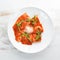 Classic Ravioli with Tomato Sauce and Parmesan Cheese. Italian cuisine. Dumplings. In a plate on a wooden background.