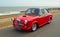 Classic Red & Black Riley 1.5 motor car parked on seafront promenade.