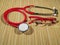 Classic red stethoscope and red glasses on a simple organic bamboo table. Health care and medicine concept