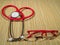 Classic red stethoscope and red plastic frame glasses on a simple organic bamboo table. Health care and medicine concept