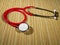 Classic red stethoscope on a simple organic bamboo table. Health care and medicine concept