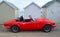 Classic Red Triumph Spitfire Motor Car Parked on Seafront Promenade parked in front of beach huts.