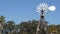 Classic retro windmill, bladed rotor and USA flag against blue sky. Vintage water pump wind turbine, power generator on livestock